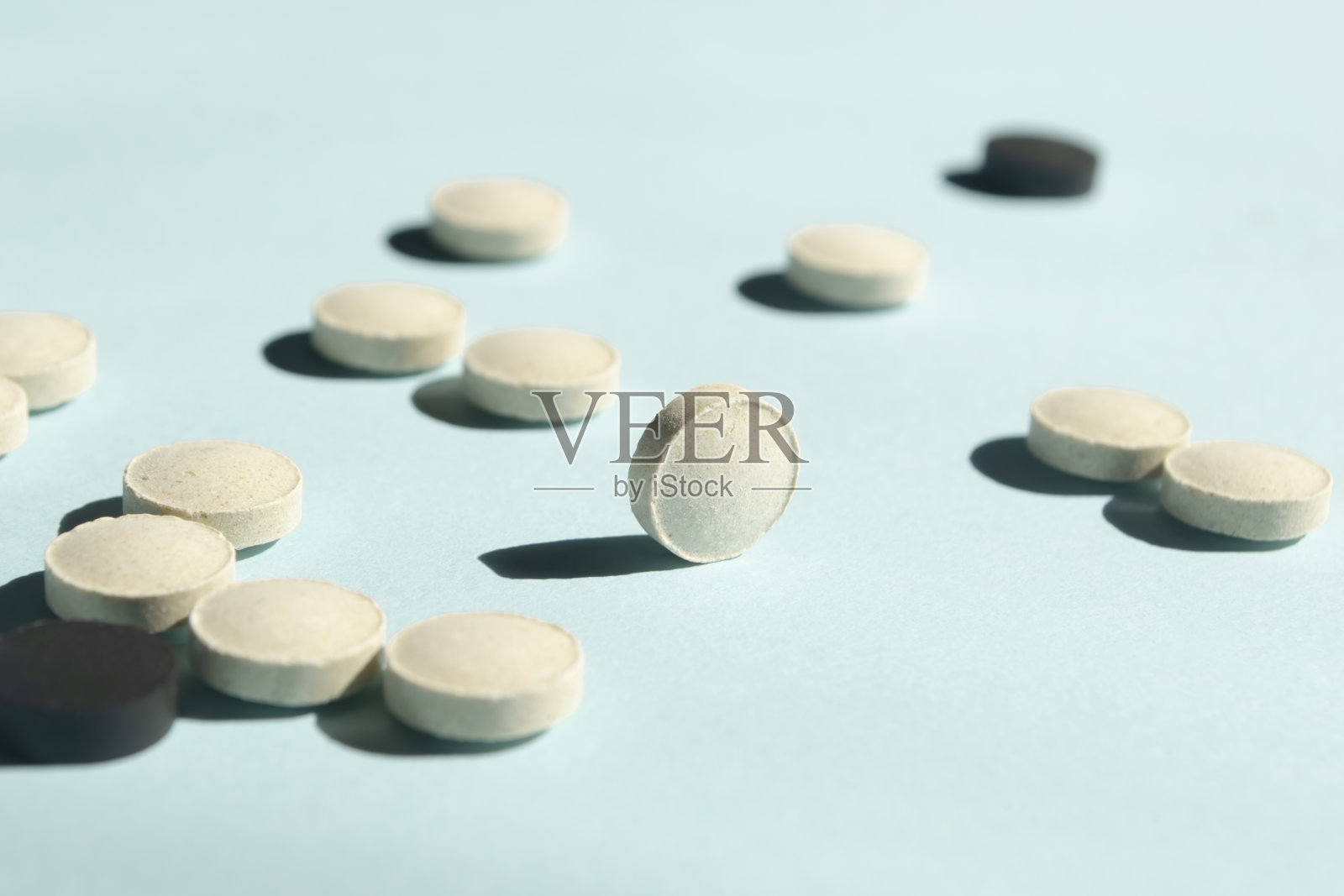 蓝色背景上的黑白药丸,零散摆放,保健美容药品照片摄影图片