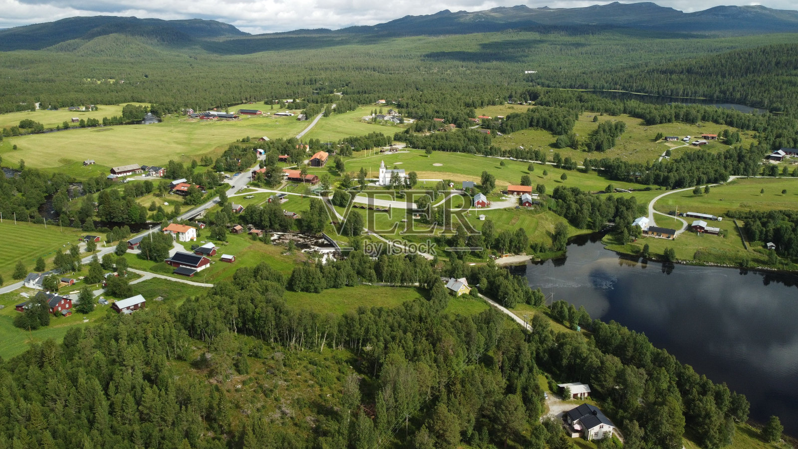 鸟瞰一个风景如画的小镇,坐落在一个宁静的湖泊旁边,周围是郁郁葱葱的绿色森林照片摄影图片