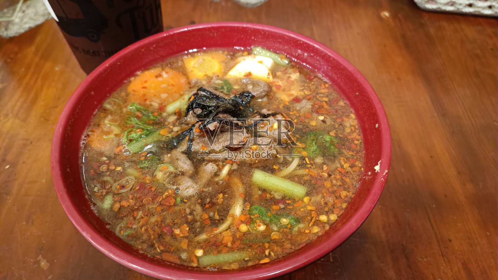 一碗牛肉拉面,配上鸡蛋和蔬菜,用勺子和筷子端上来照片摄影图片