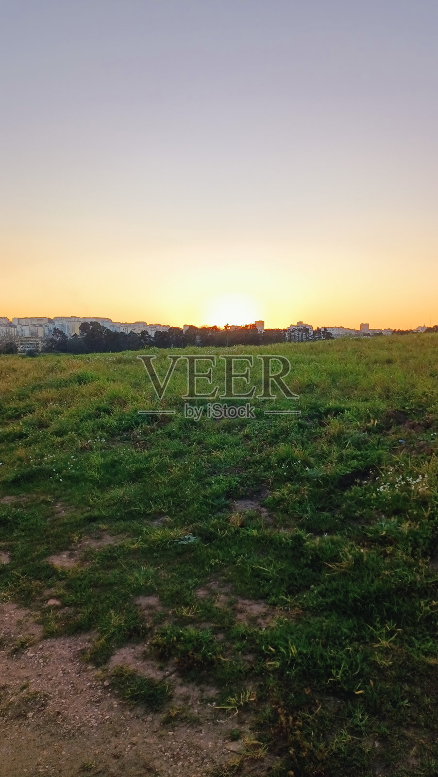 徒步穿过一片田野,你可以看到日落和地平线上的城市照片摄影图片