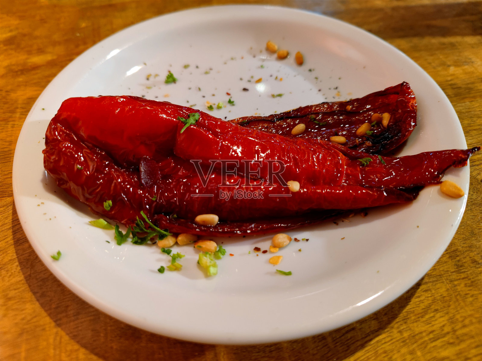 餐厅桌子上的白板上放着美味的红甜尖椒钟,配上新鲜的香草和松子照片摄影图片