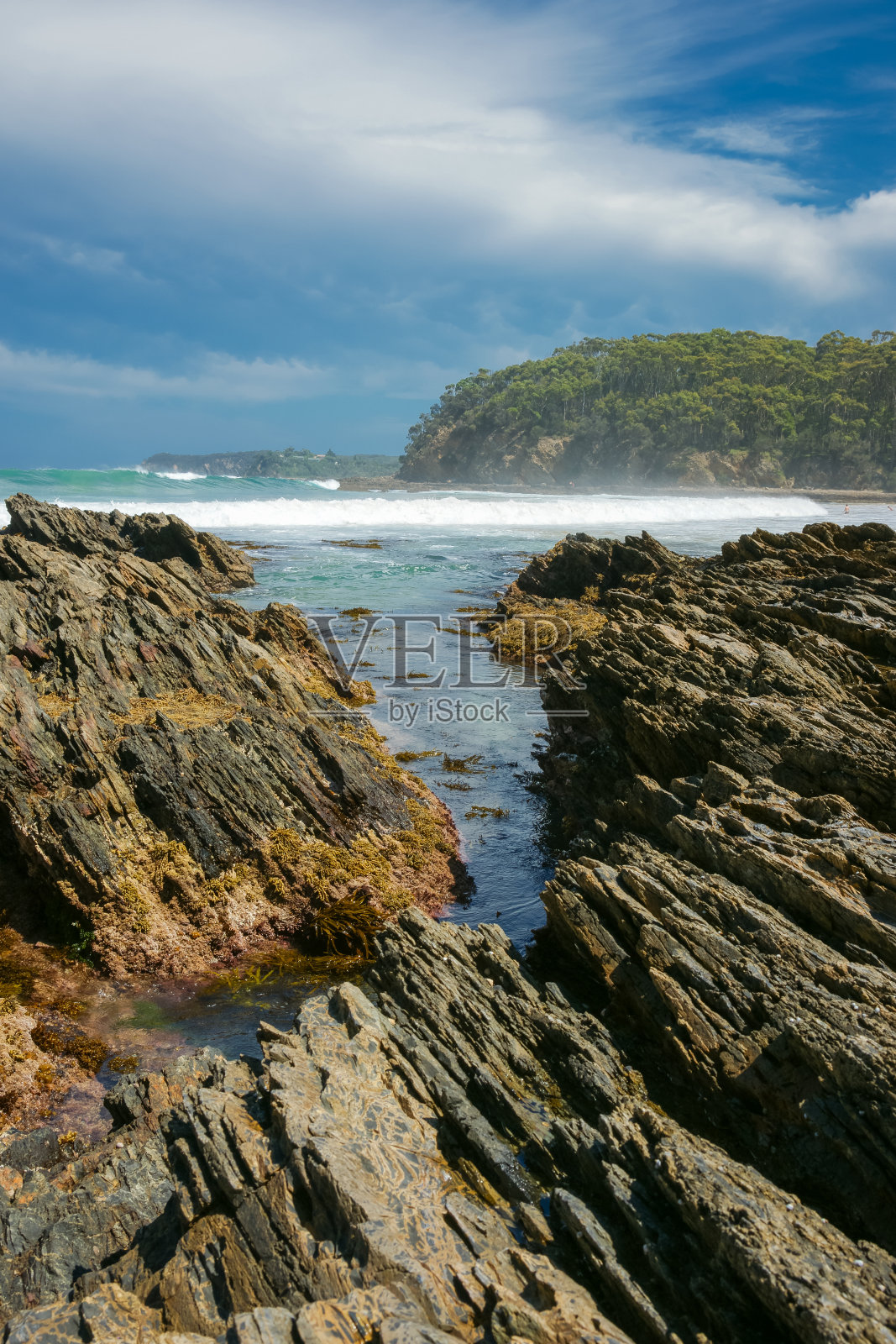 崎岖多岩石的前海岸,在岩石入口之外有大浪照片摄影图片