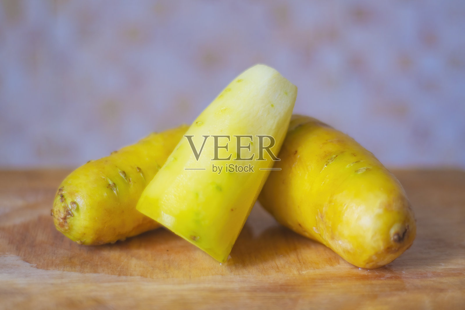 一块旧厨房板上放着一根去皮的黄色胡萝卜。照片摄影图片