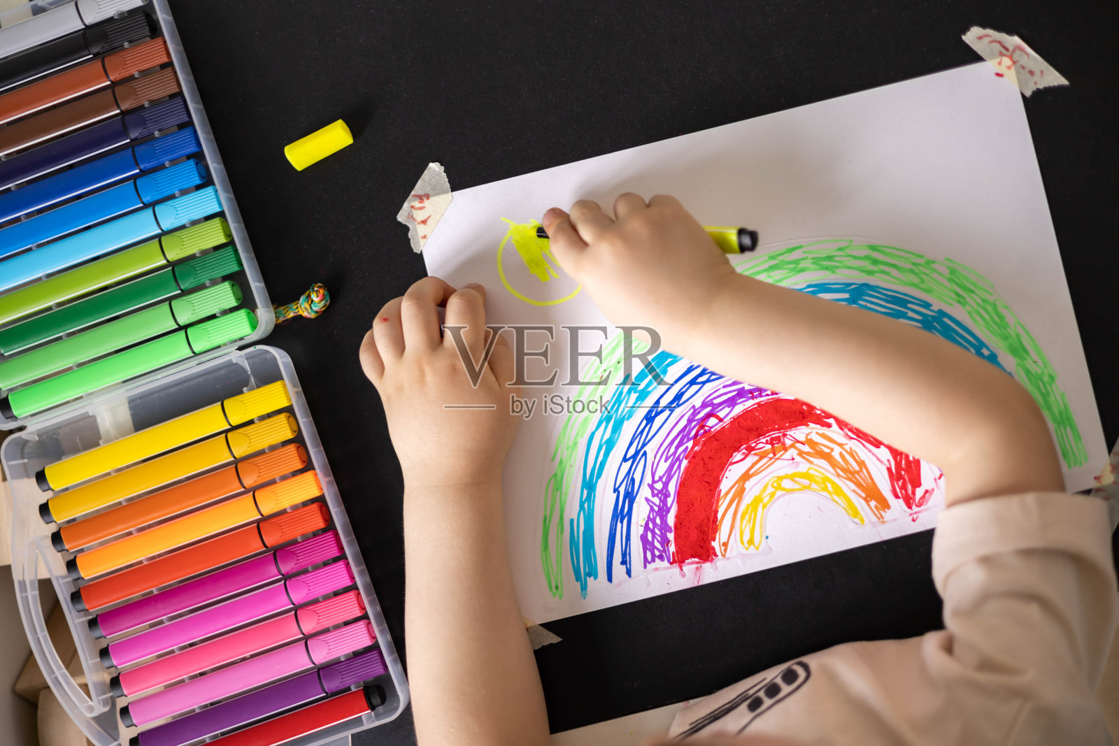 可爱的男性孩子在纸上画彩色彩虹拱使用彩色感觉笔尖顶部视图照片摄影图片
