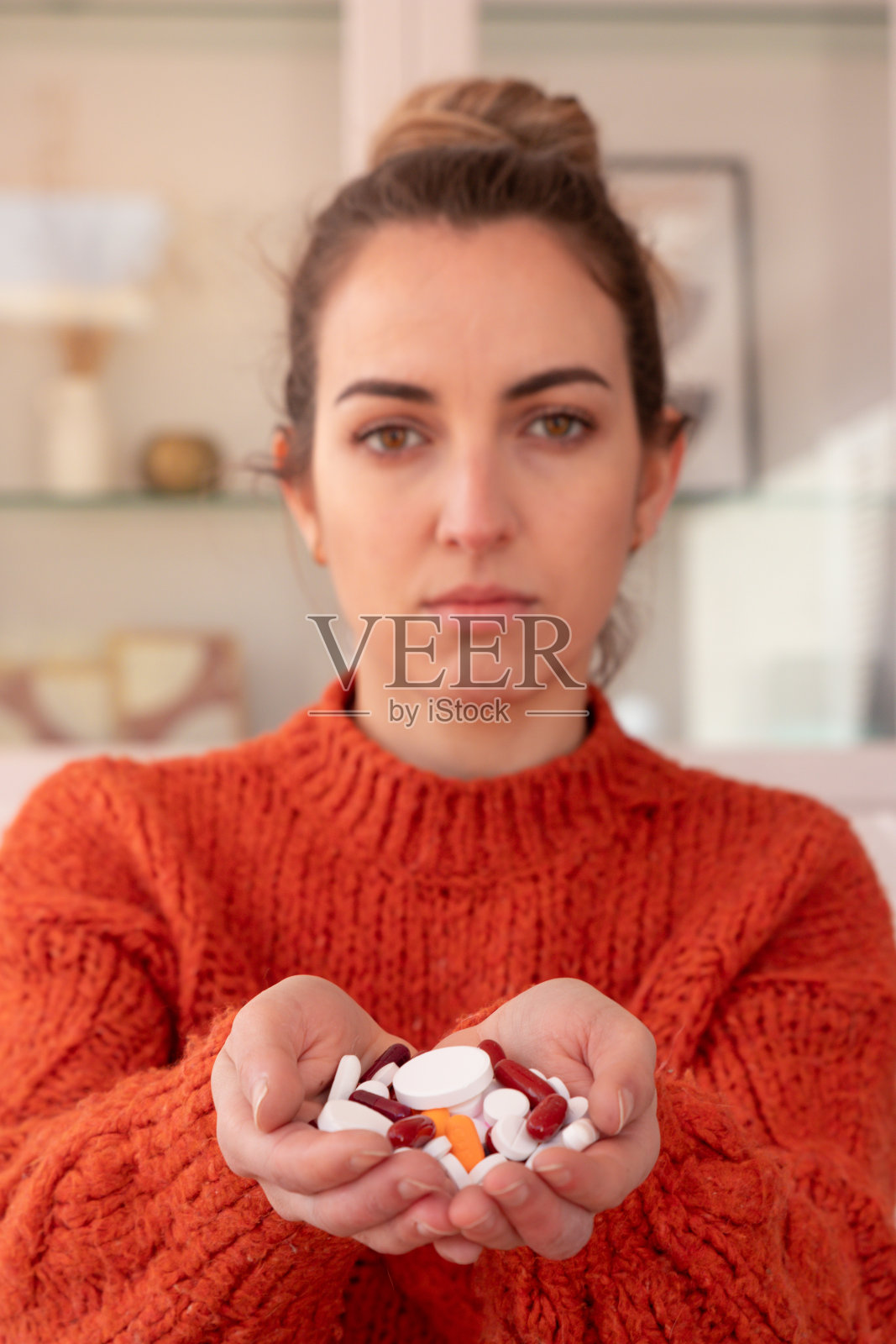 年轻的女性显示一把各种药物和药物,而坐在家里,看着相机照片摄影图片