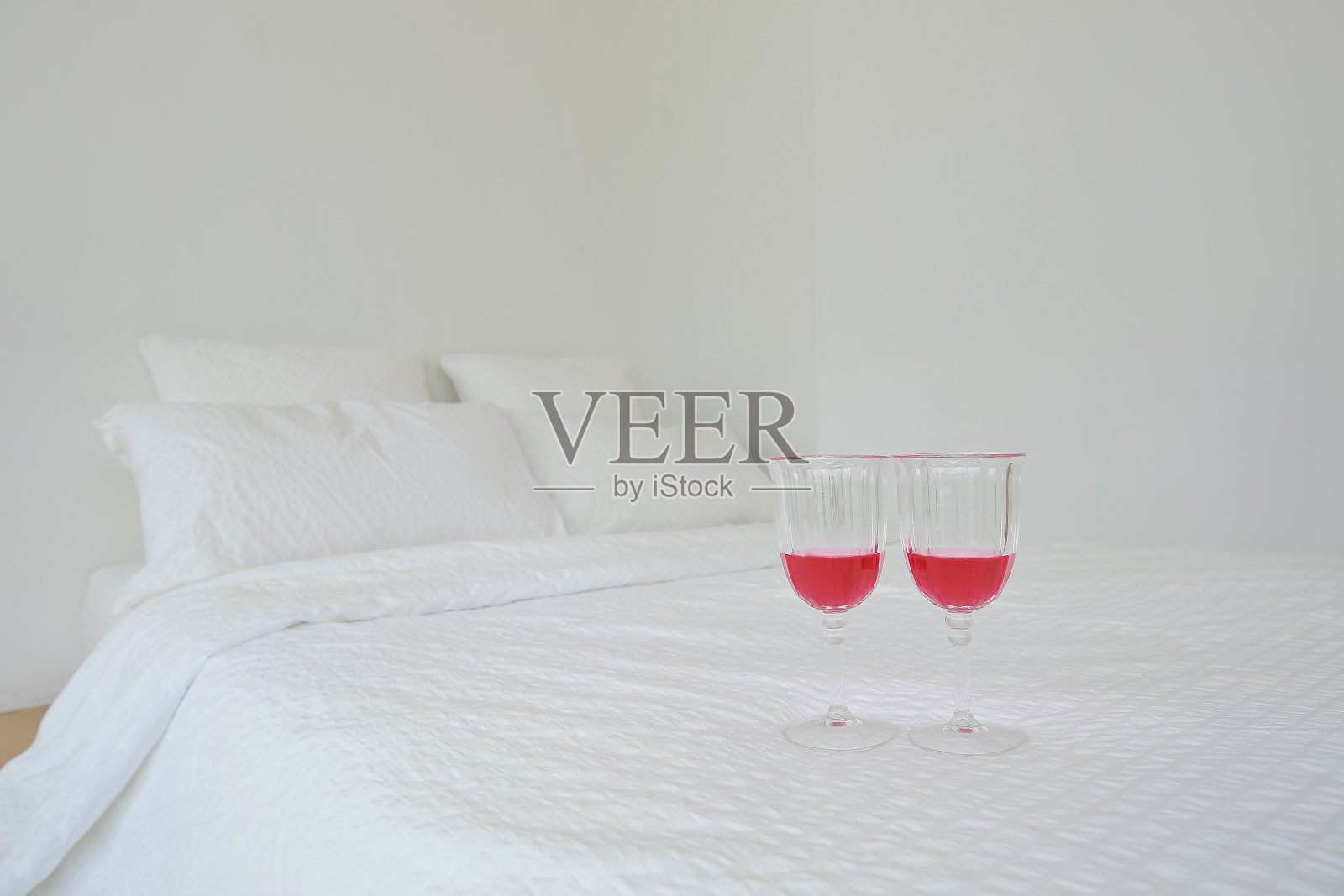 当酒杯洒出来时,白色的床上用品和白色的枕头会弄得一团糟照片摄影图片