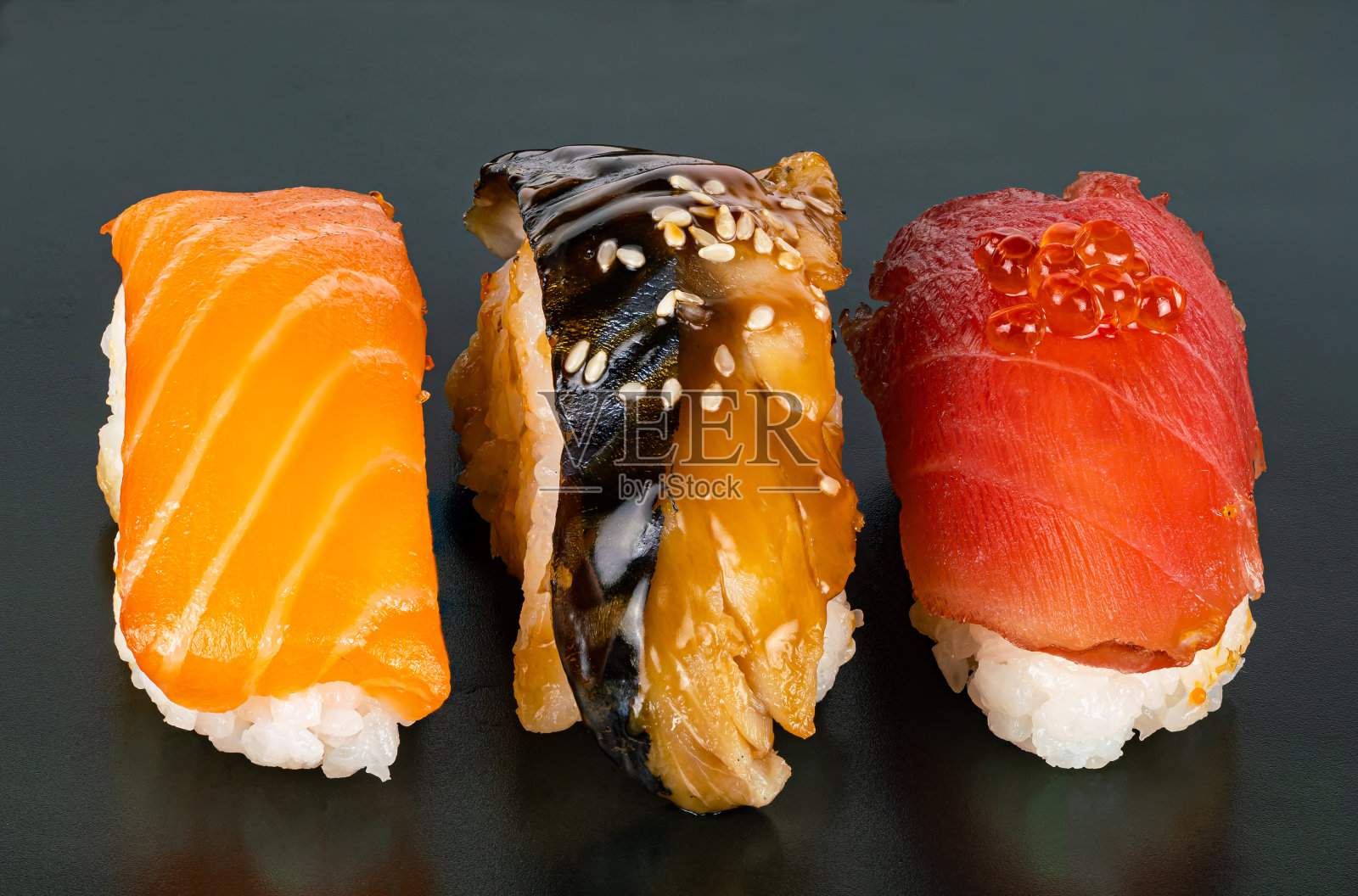 近距离观看三种鱼类刺身寿司在黑暗的背景。照片摄影图片