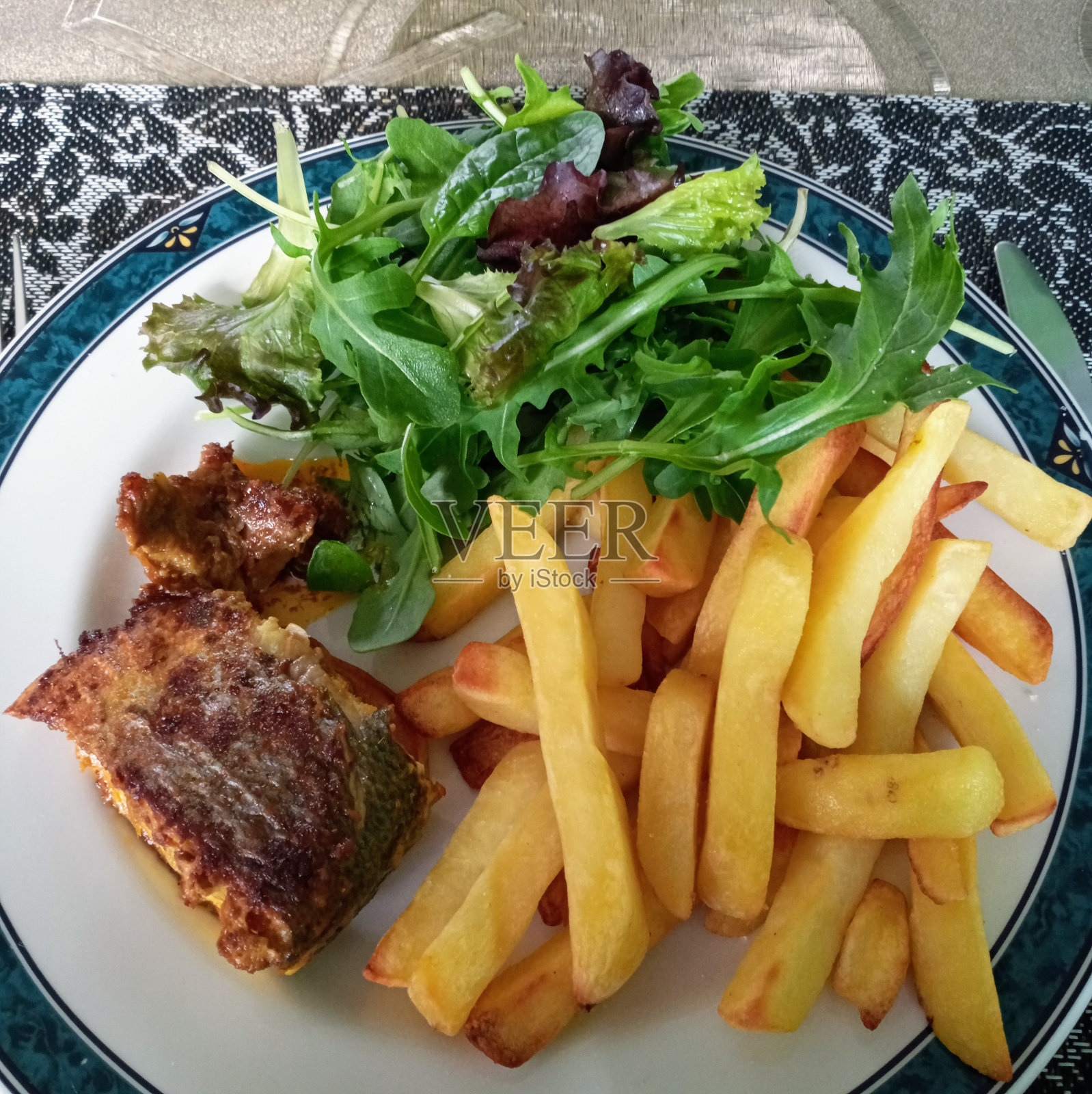 辣鲈鱼,薯条配什锦沙拉。照片摄影图片