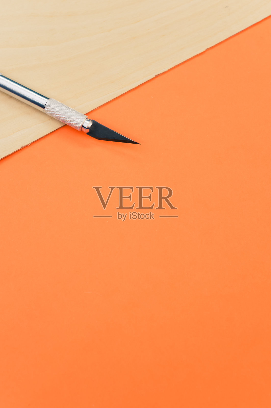 垂直拍摄的金属手术刀在胶合板表面隔离在橙色背景照片摄影图片