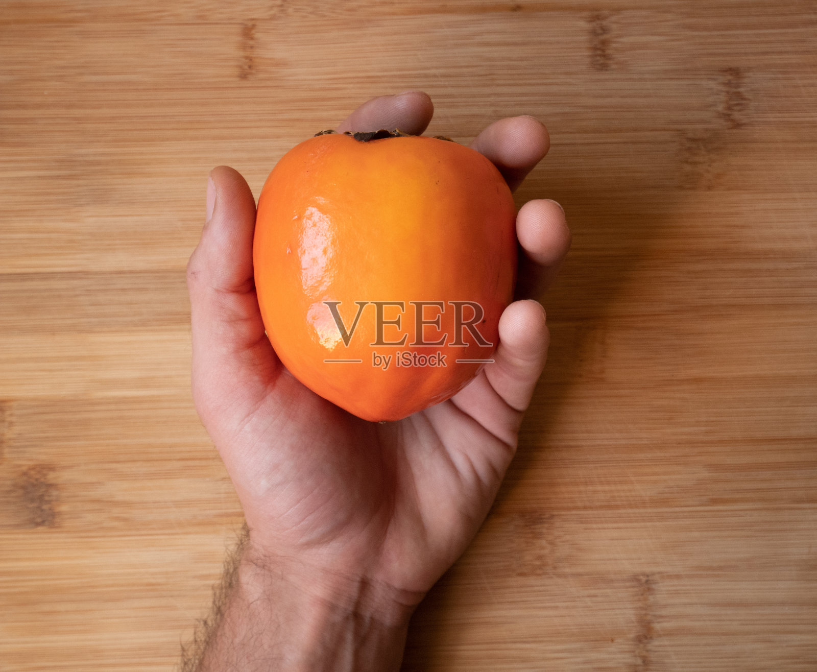 一个人在木桌上拿着一个柿子的俯视图照片摄影图片
