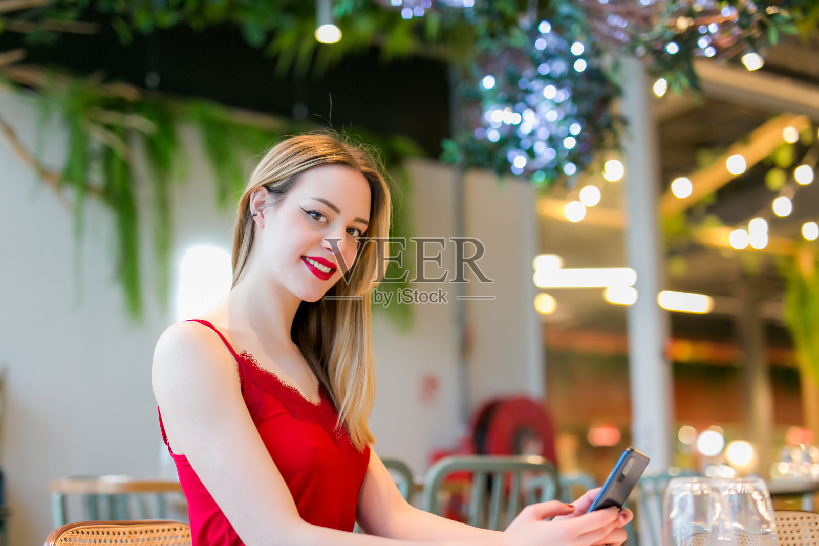 快乐的女人在餐厅吃早餐时查看智能手机照片摄影图片