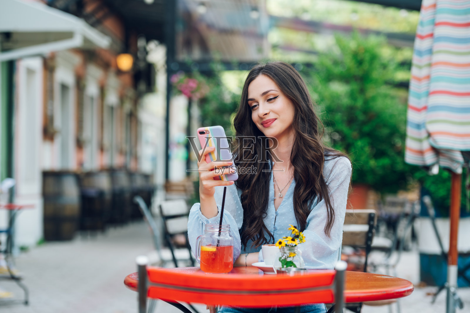 一个美丽的女人坐在街头咖啡馆和使用智能手机的肖像照片摄影图片