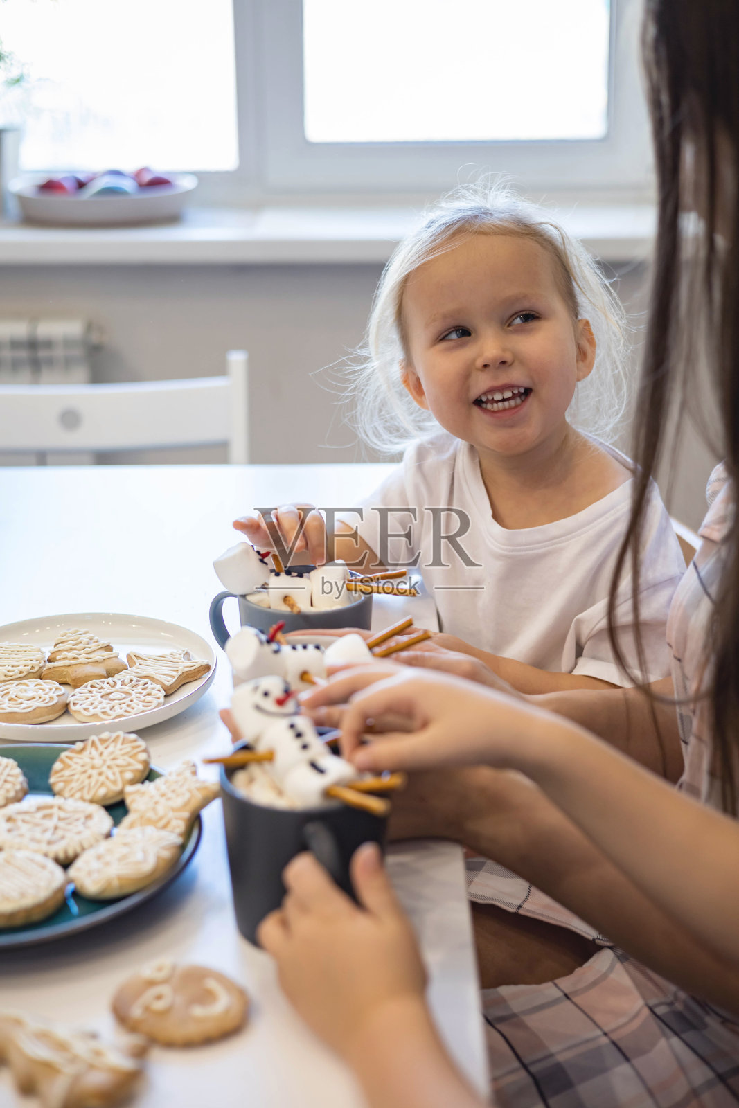 妈妈和孩子们用棉花糖堆雪人。他们喝着可可,为圣诞节做准备。圣诞之家概念。照片摄影图片
