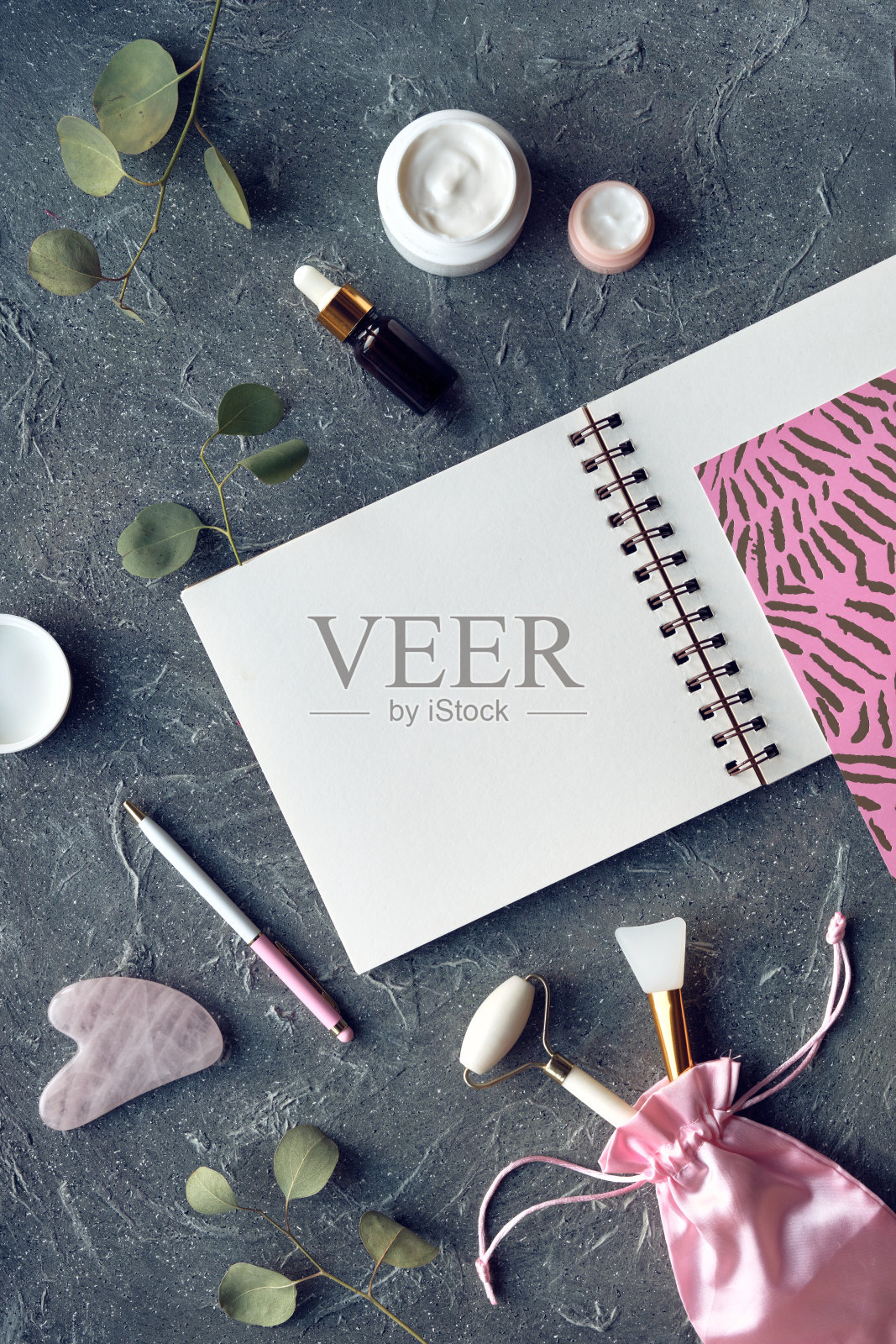 面部按摩辊、瓜沙石、精油、保湿霜、蚕丝面膜、晚霜。笔记本上的空白页为你的文本。照片摄影图片