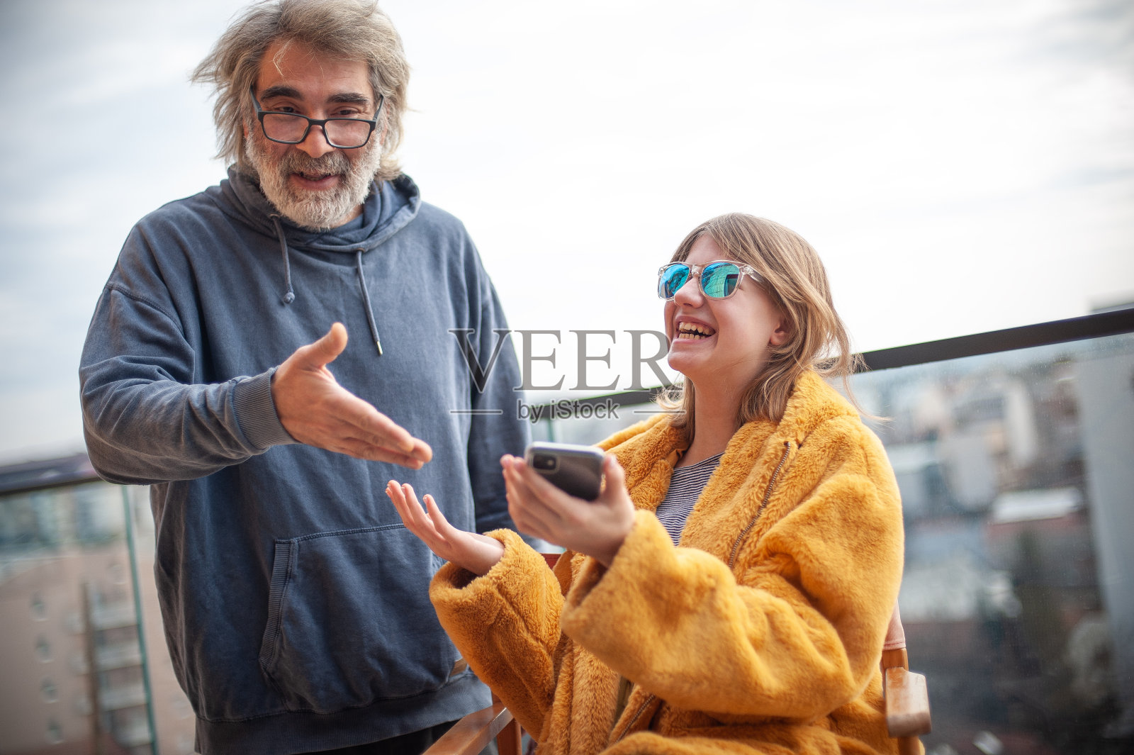 英俊的父亲,开朗的女儿在阳台上玩手机照片摄影图片