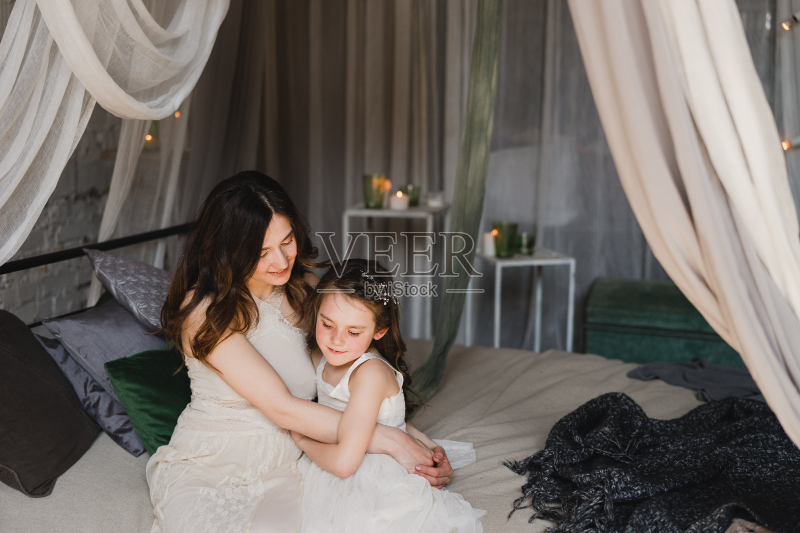 幸福的白人母女在室内的床上拥抱、拥抱、拥抱。祝您母亲节快乐。漂亮的小女孩和漂亮的女人躺在一起。照片摄影图片