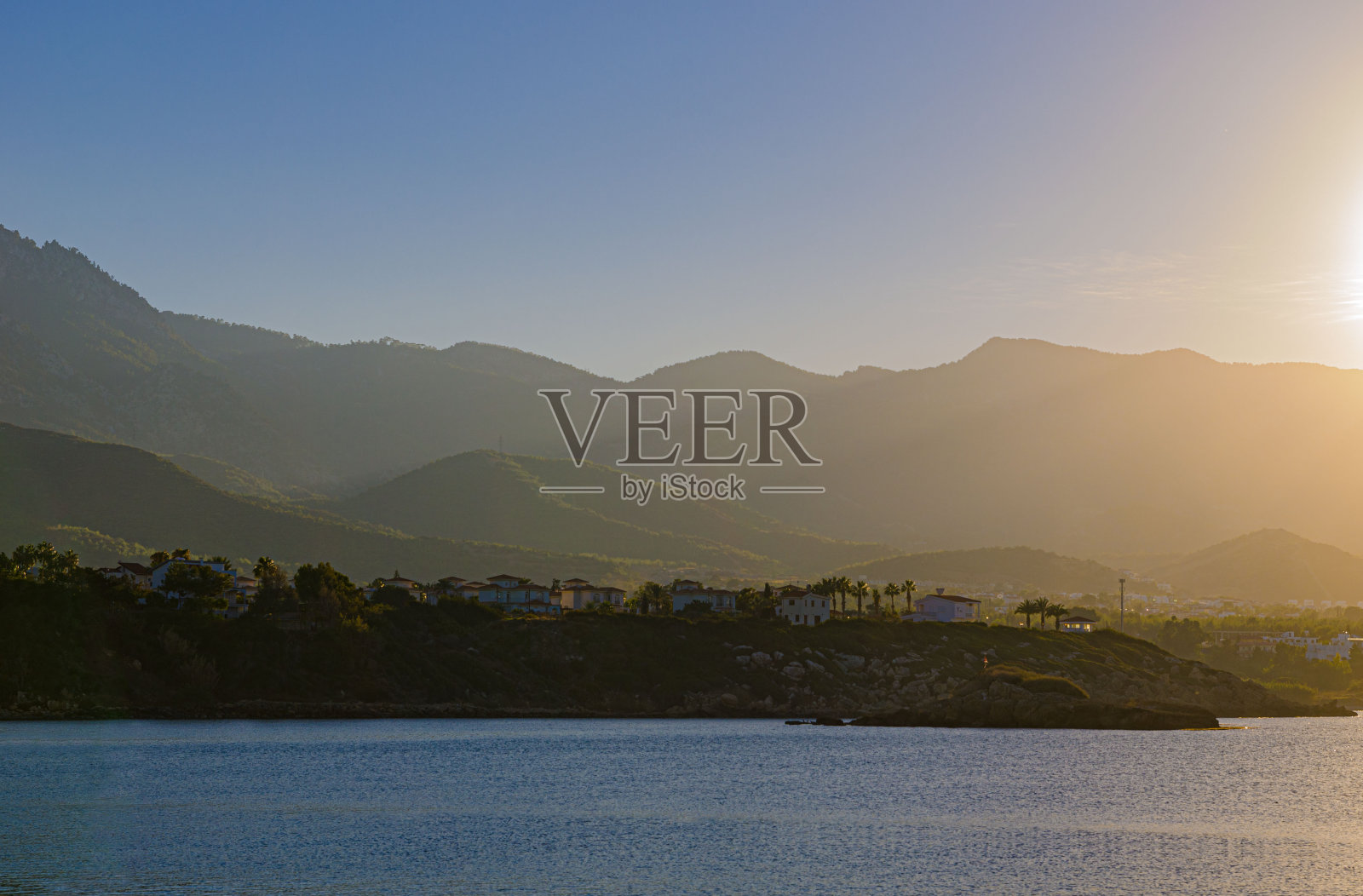 海上的日落,明亮的天空和云在左边,你可以看到山不再被太阳照亮,方向是风景,有文字的地方照片摄影图片