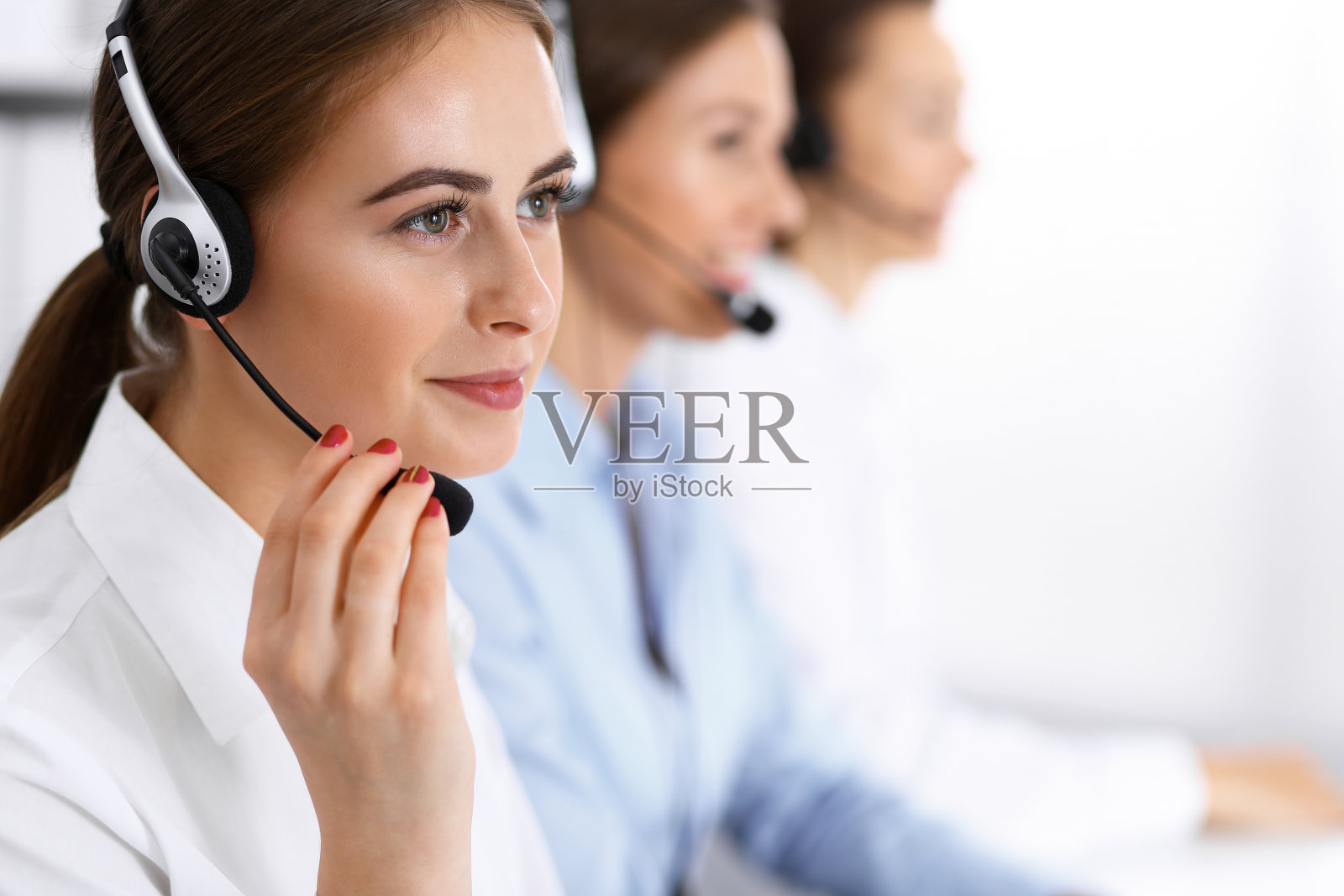 呼叫中心。一群操作员在工作。专注于戴耳机的美丽商业女性照片摄影图片