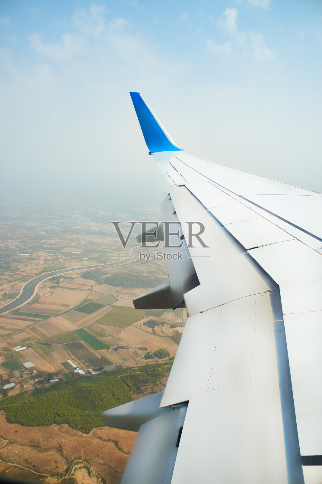 从一架正在着陆的飞机上眺望窗外。一架飞机的机翼在土耳其热带岛屿上空的云层上飞行。飞机的机翼在天空的云层上飞行照片摄影图片