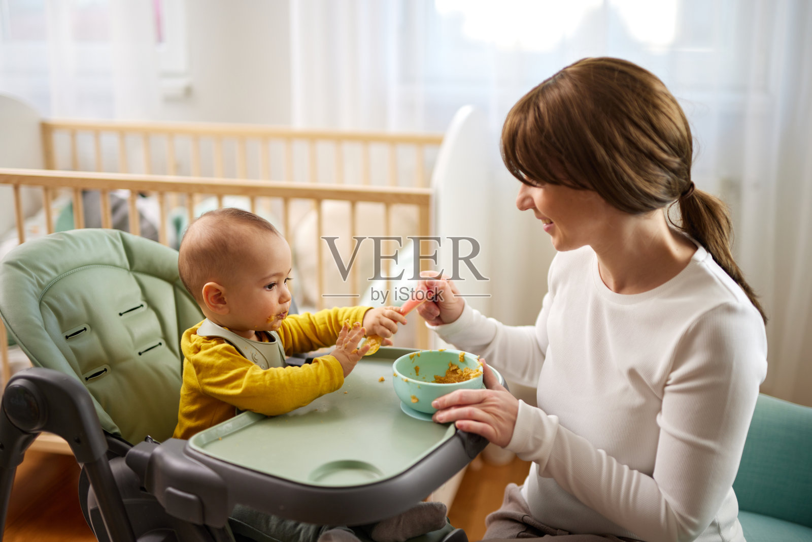 母亲在家里用勺子喂她的小儿子照片摄影图片