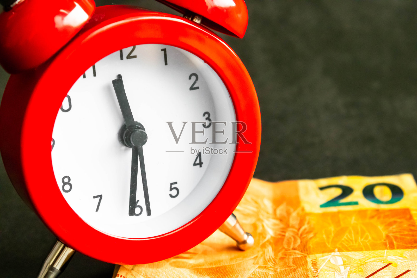 钞票前面的红色时钟,是一张20巴西雷亚尔的钞票。提到时间和金钱的关系,以及个人和公司每天付出多少时间和劳动是值得的。照片摄影图片