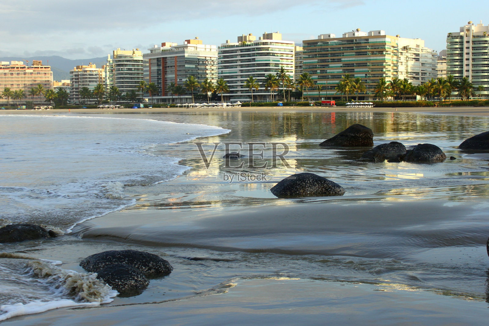 海滩蓝色的海水与晨光。海岸线上的城市建筑照片摄影图片
