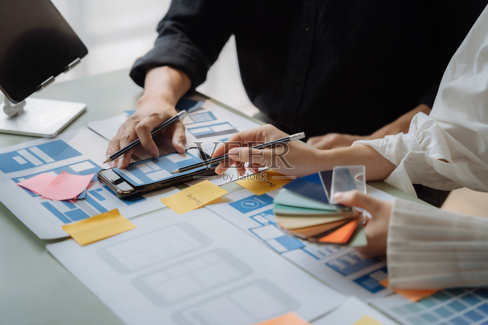 UI设计师在办公室与客户讨论移动应用程序界面线框设计和颜色代码。照片摄影图片