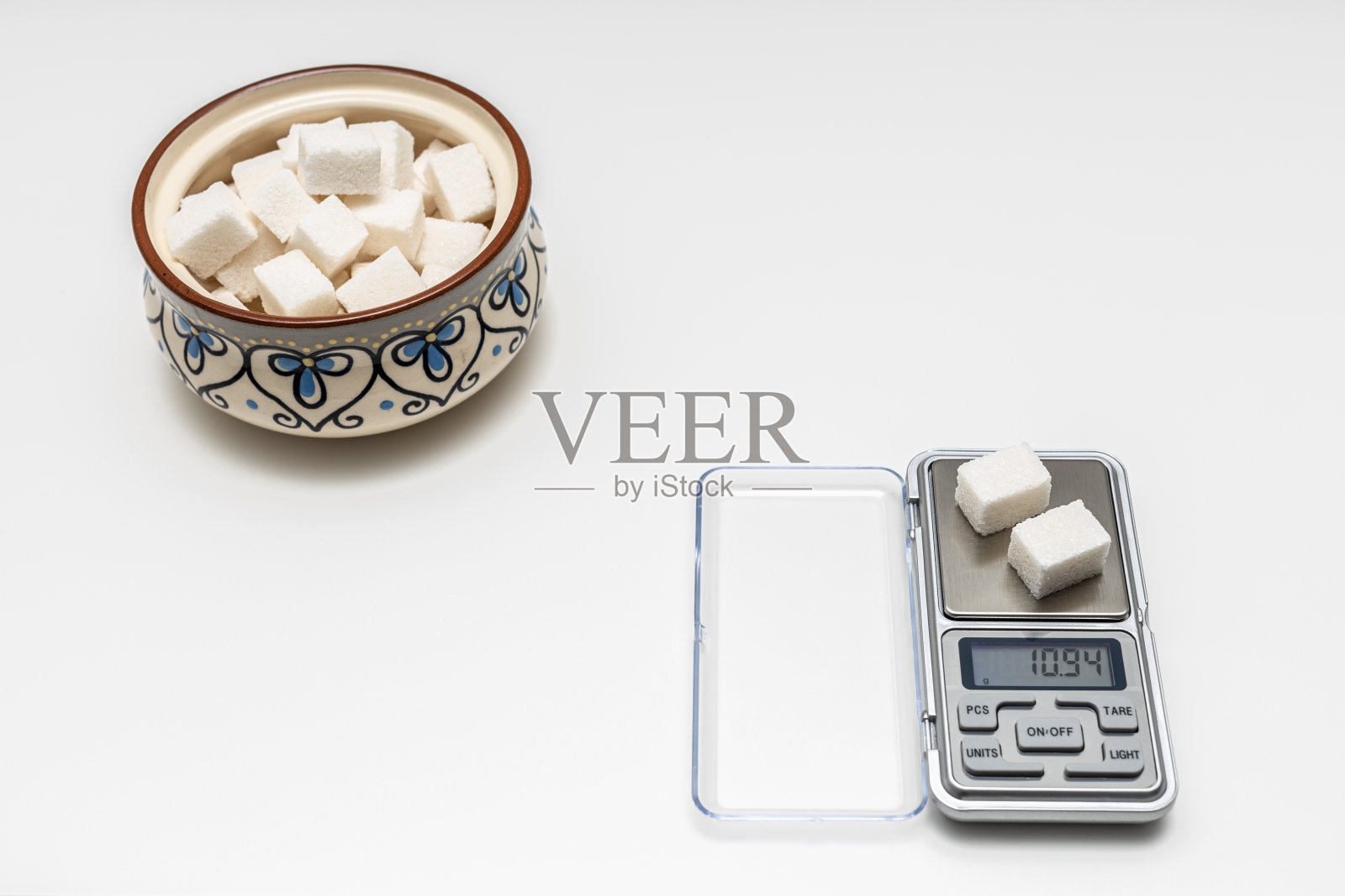 一块方糖放在一个小天平上。照片摄影图片