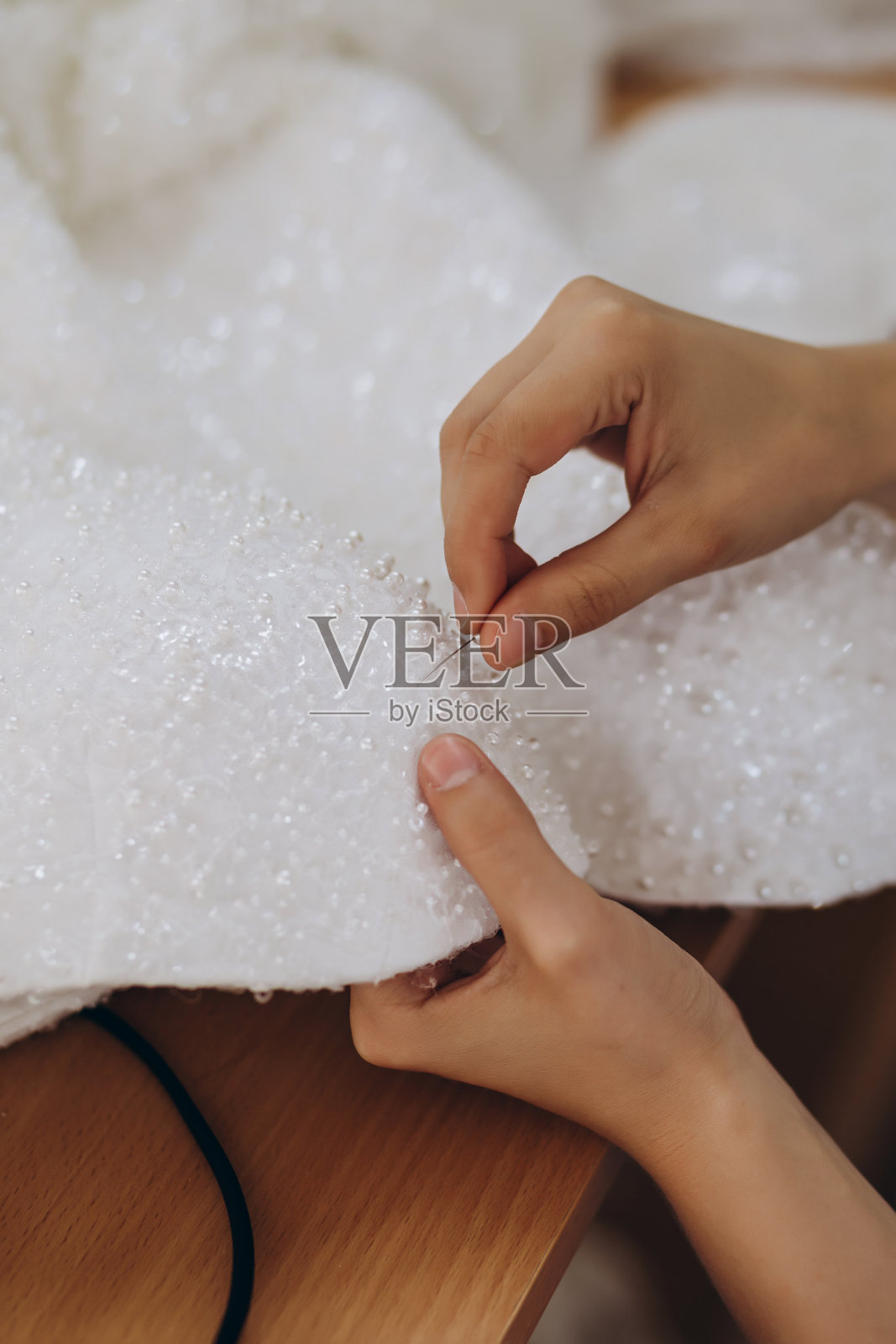 一个人正在用针缝一件新的白色连衣裙。照片摄影图片