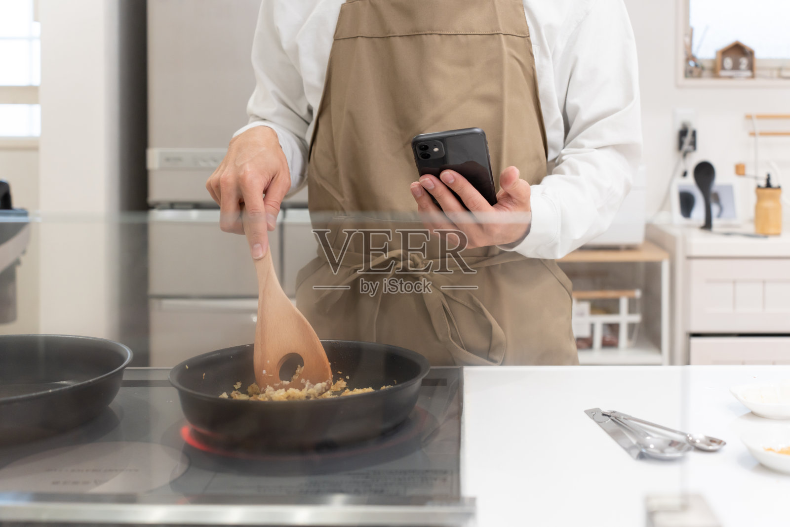 40多岁的男人在厨房用智能手机做饭照片摄影图片