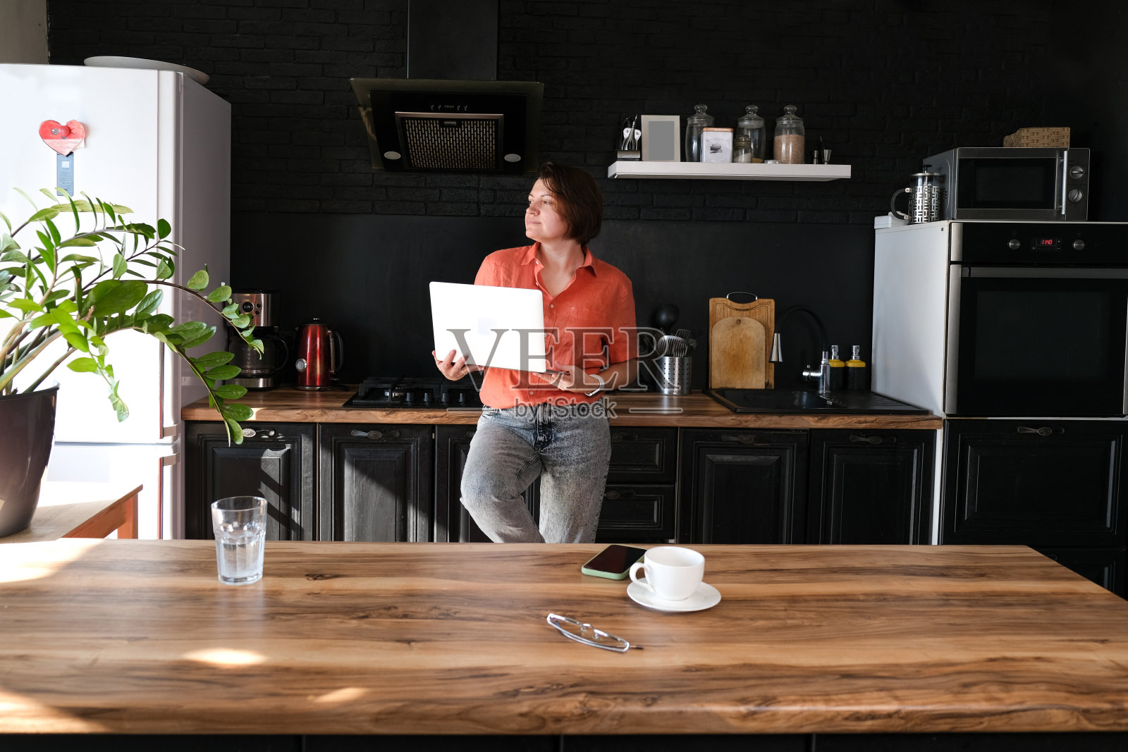 妇女工作与笔记本电脑在家里在厨房背景。自由职业者在家办公的概念。照片摄影图片