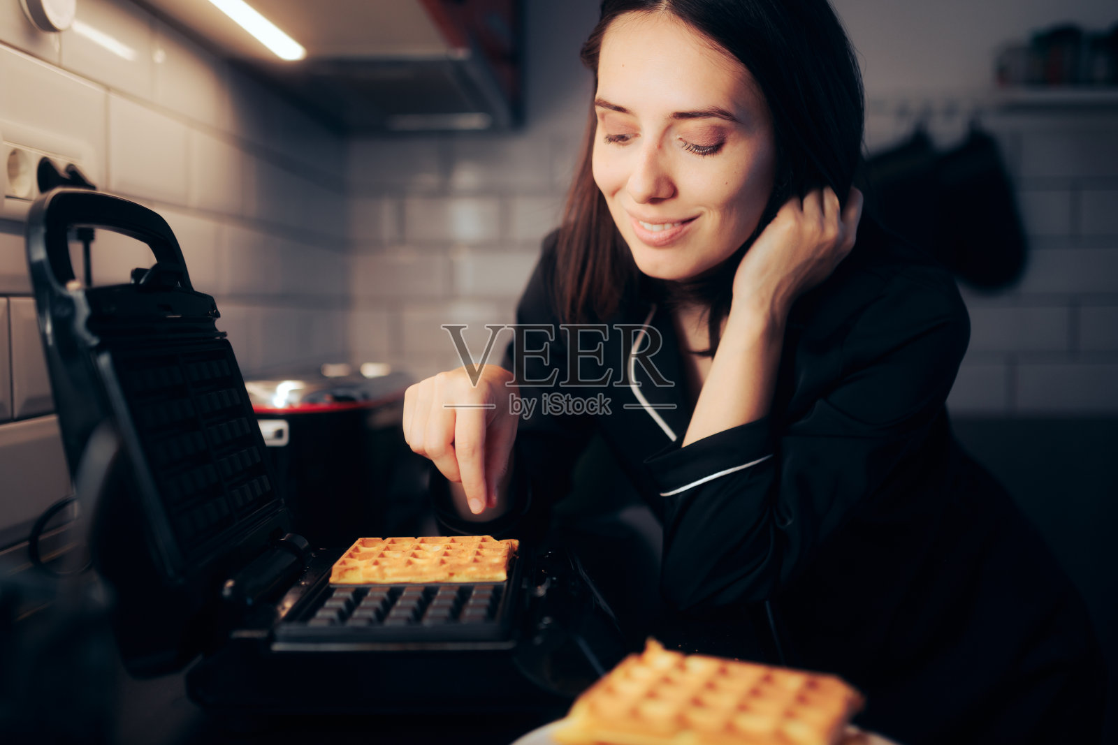 女人从烹饪机里拿出华夫饼照片摄影图片