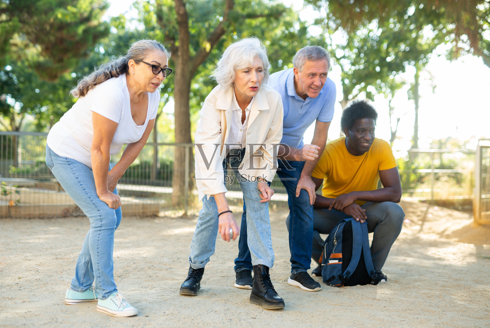 无忧无虑的多种族朋友在公园的沙滩上扔金属球照片摄影图片