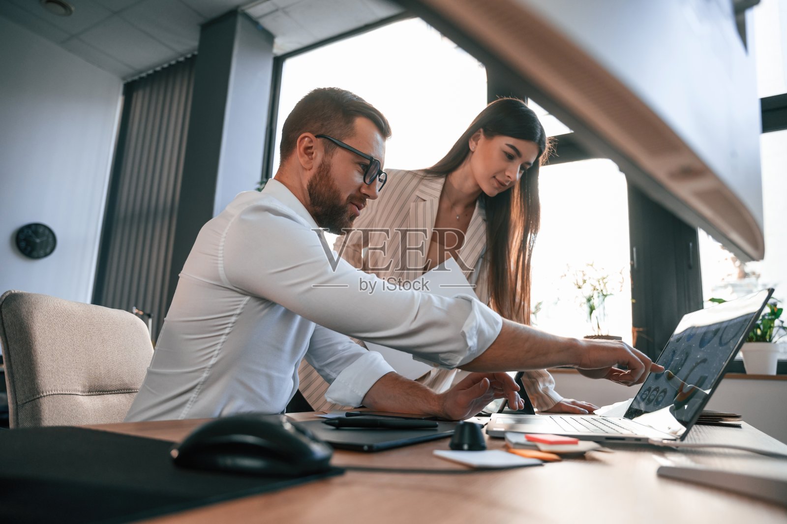 侧视图。论文工作。两个雇员在一个现代化的办公室里照片摄影图片