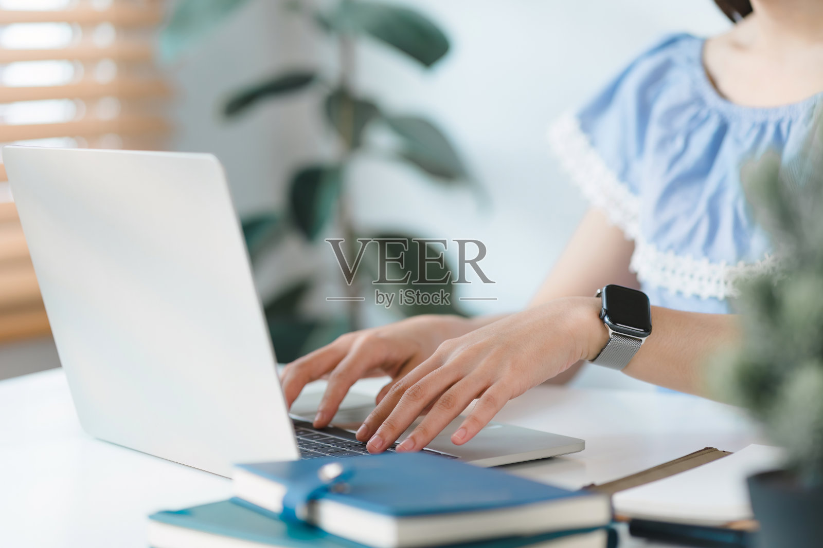 一个女性在她舒适的家庭办公室里用笔记本电脑工作的手特写。照片摄影图片