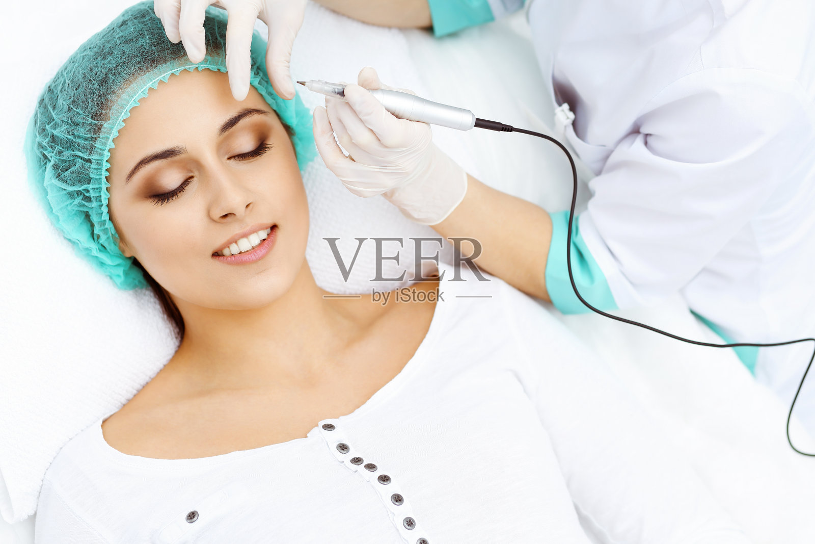 专业美容师在女人脸上做眉纹。在美容院的永久眉妆,特写。美容治疗照片摄影图片