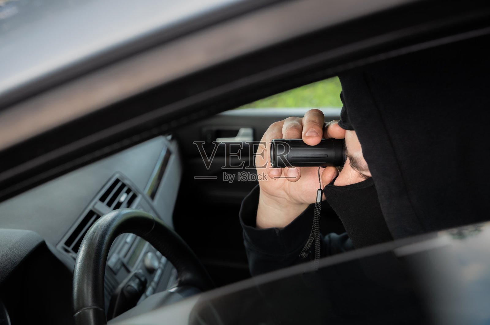 在车里监视。穿黑衣服,拿双筒望远镜的男人。犯罪的概念。侦探工作。照片摄影图片