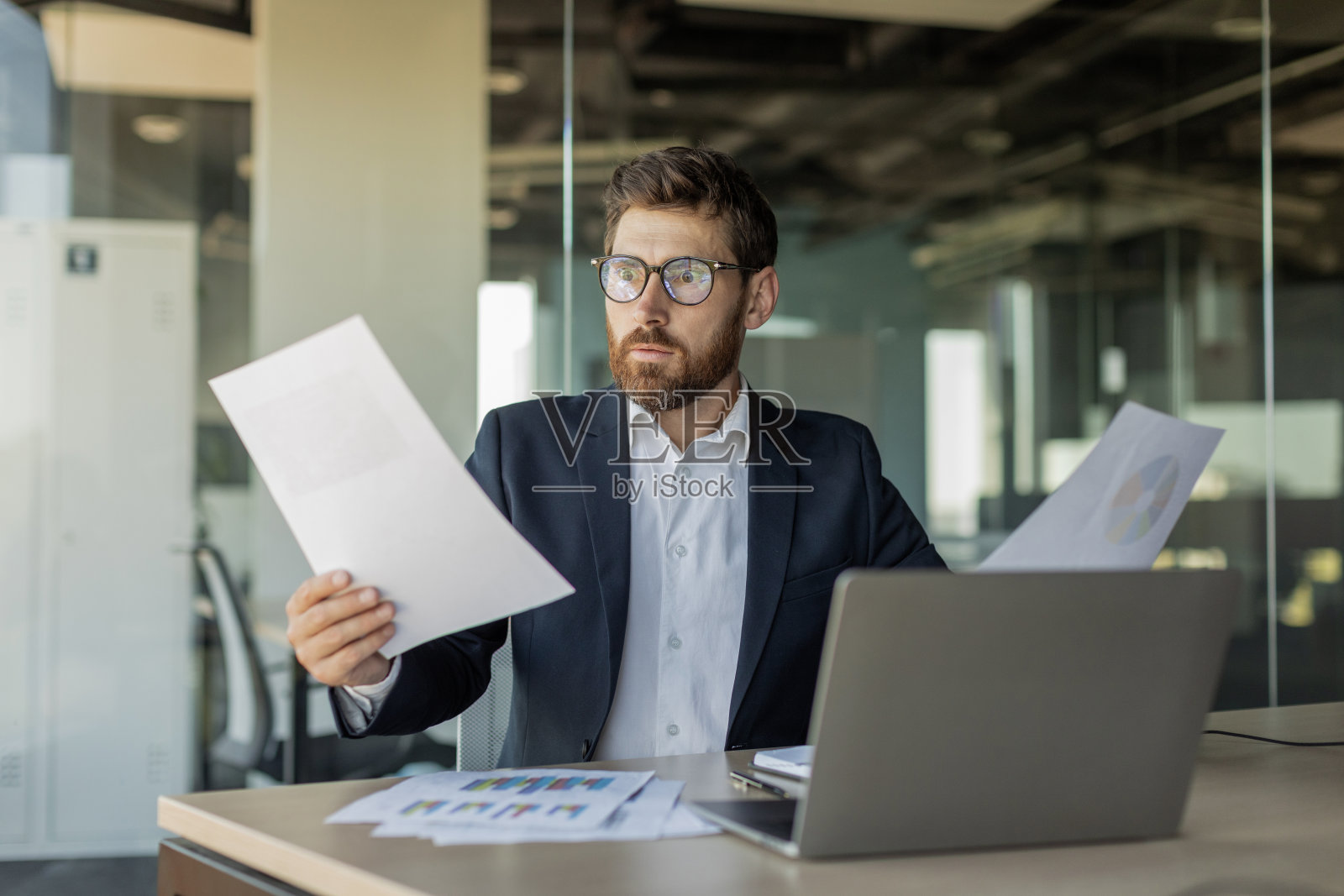 震惊的成熟商人阅读文件,有问题的报告,在办公室用笔记本电脑工作照片摄影图片