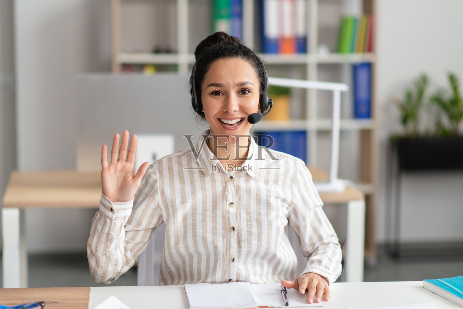 戴着耳机进行视频通话并挥手的快乐女人 портрет照片摄影图片