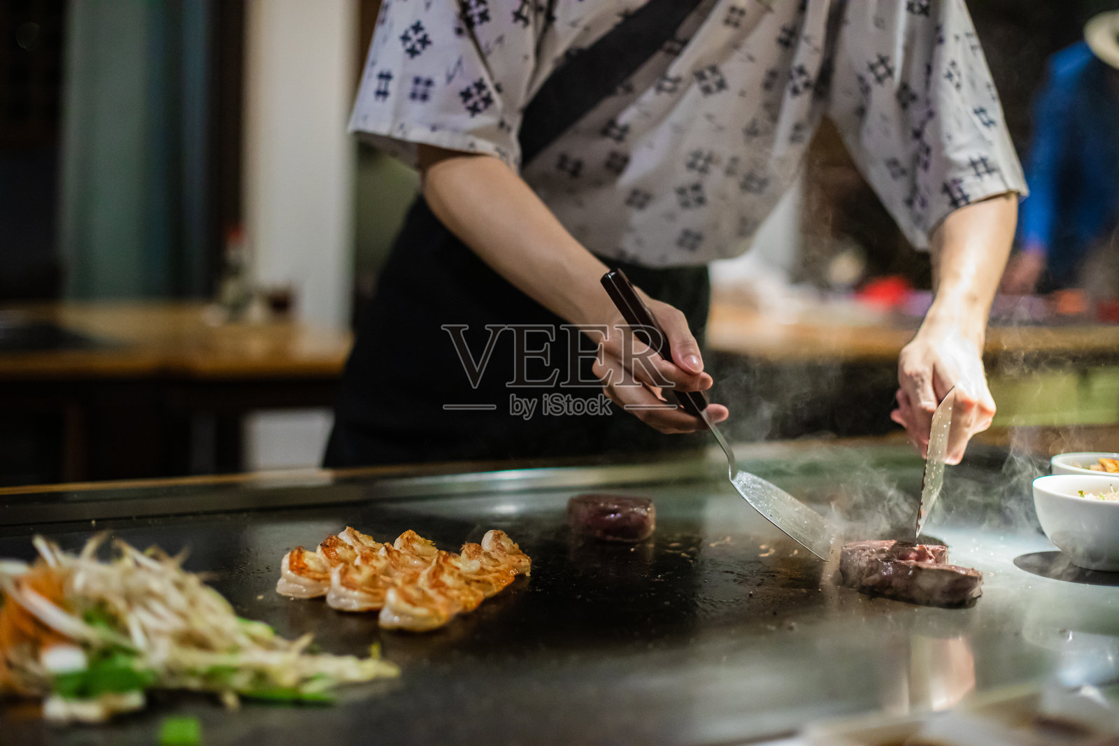 铁板烧——在平底锅上烤牛肉。厨师在热腾腾的餐桌上做饭照片摄影图片