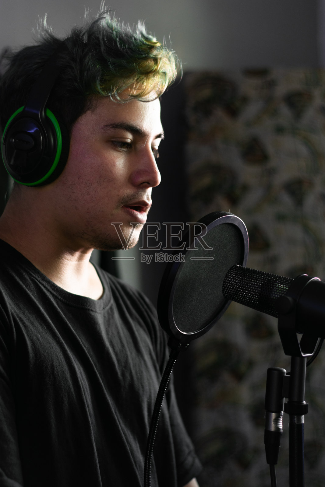 一名拉丁青年在录音棚的麦克风前戴着耳机照片摄影图片