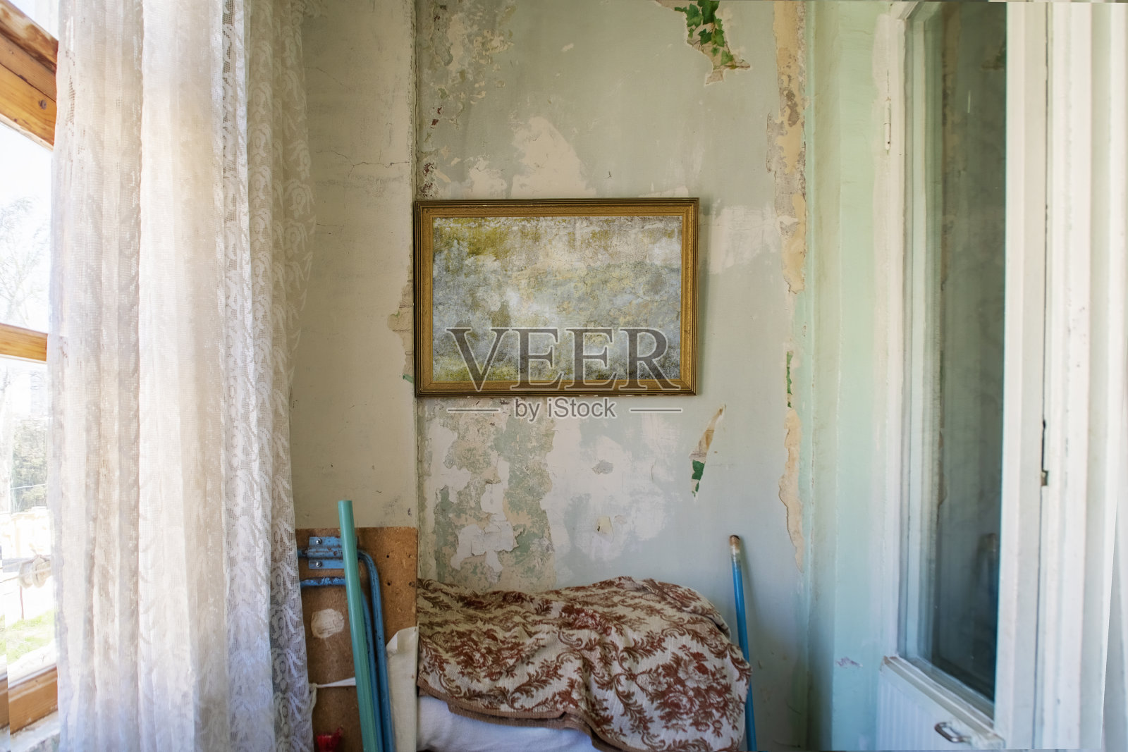 在一间破旧的白色墙壁的旧房间里,一个空画框。中亚或东欧的贫困住房。照片摄影图片