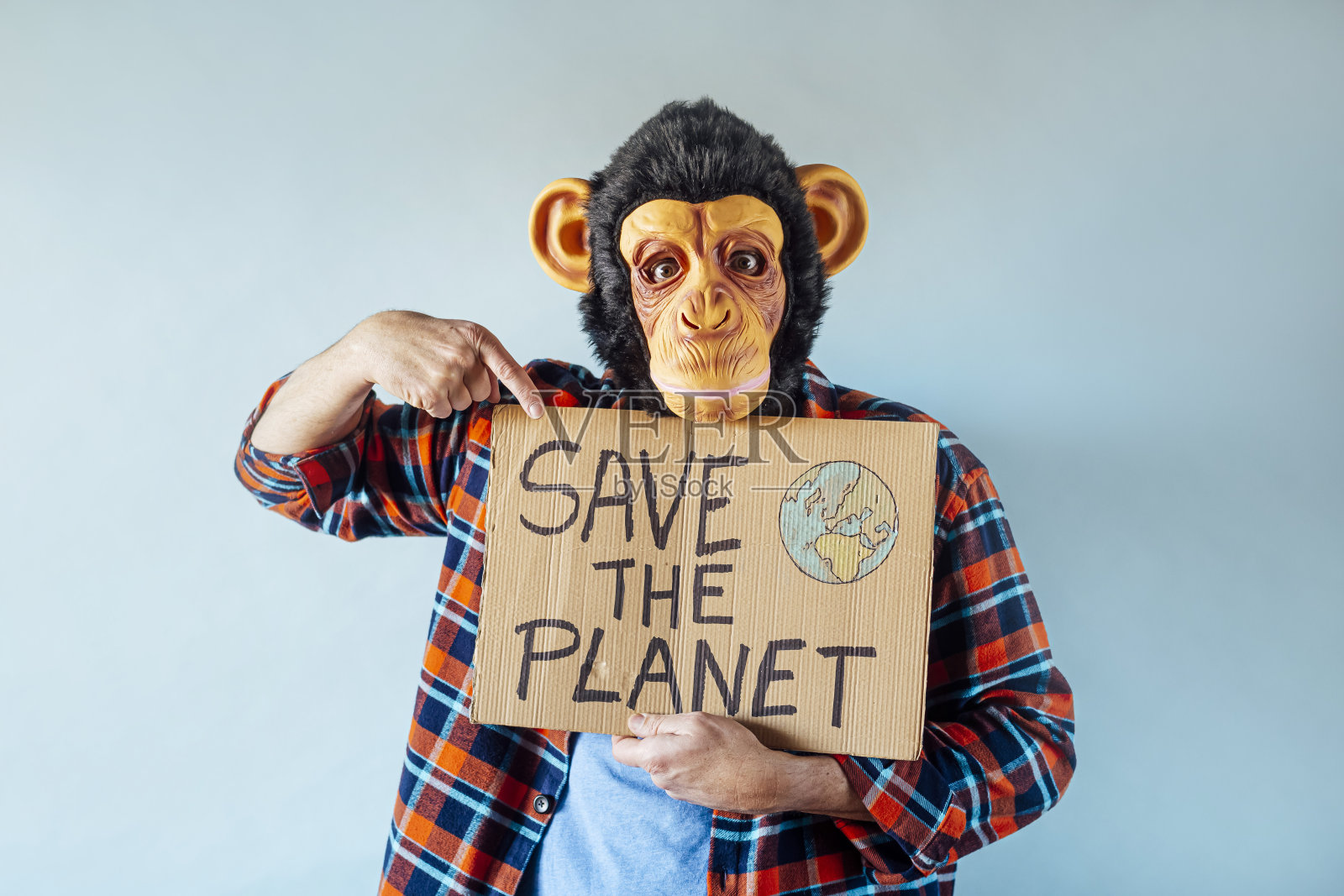 带着猴子面具的男子举着一个写着“拯救地球”的牌子。照片摄影图片