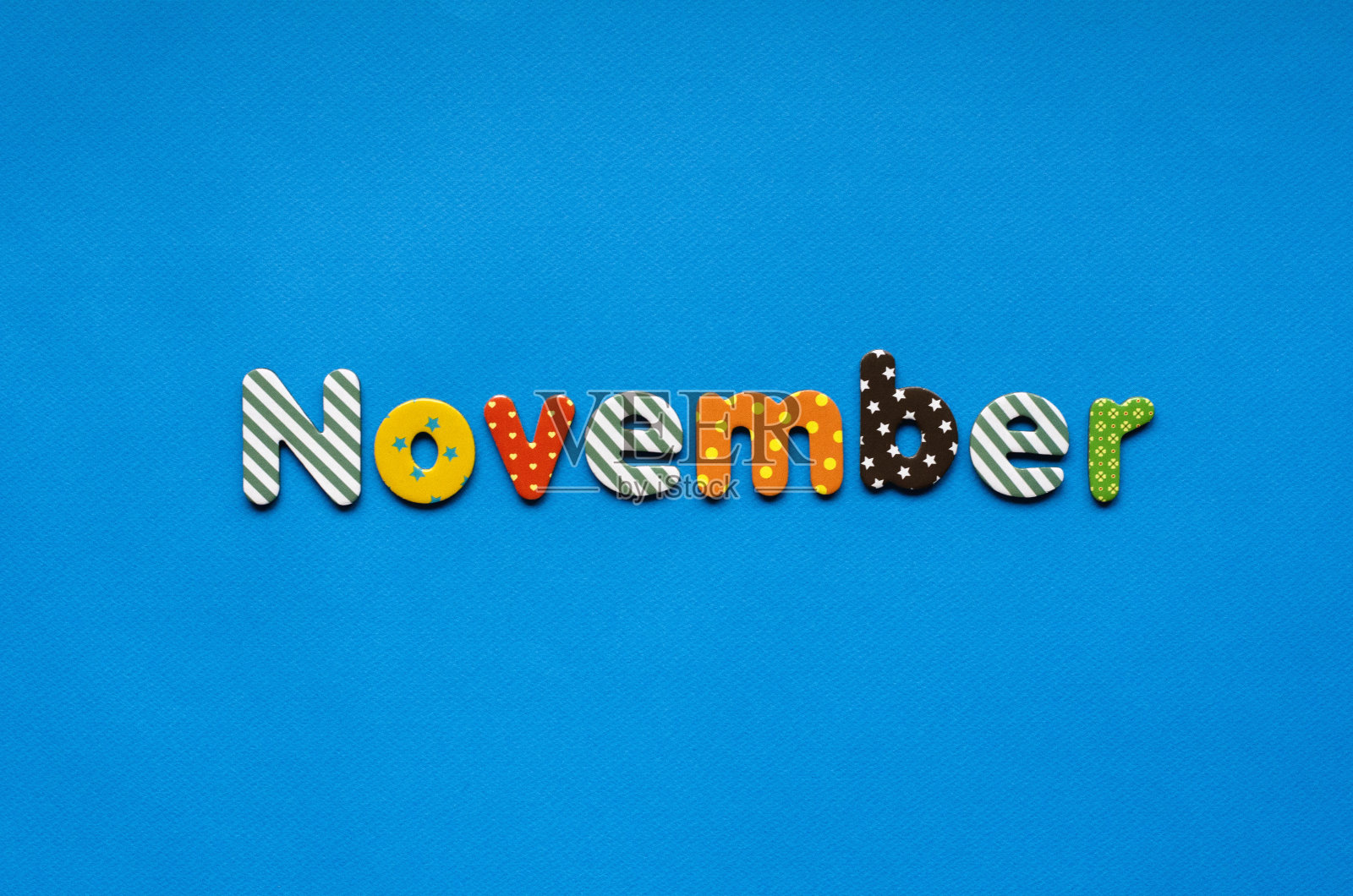 蓝色纸背景上的彩色文字十一月照片摄影图片
