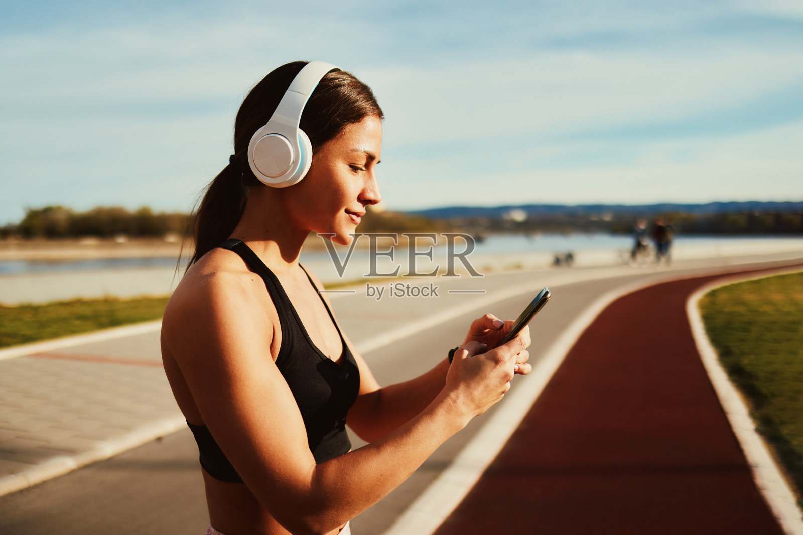 年轻的健身女士准备慢跑,用智能手机选择音乐照片摄影图片