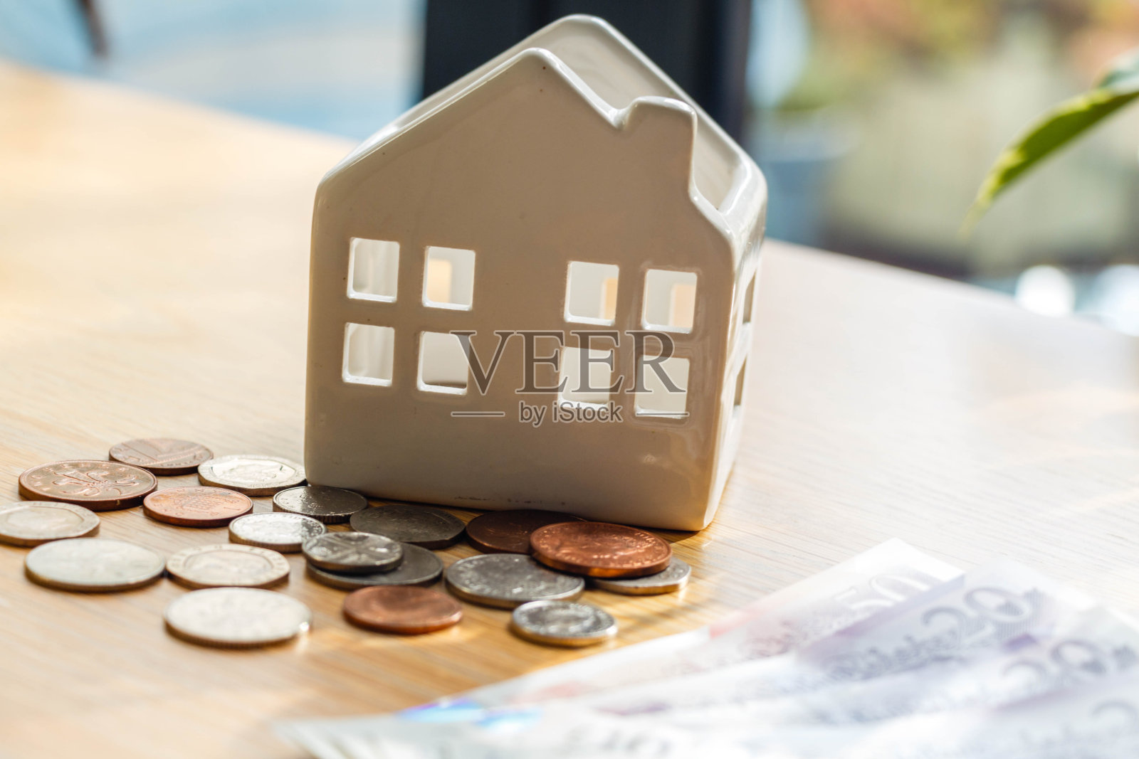 一个储蓄罐陶瓷房子旁边躺着一枚英国硬币照片摄影图片