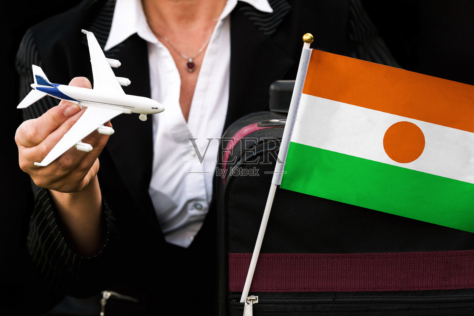 女商人拿着玩具飞机旅行袋和尼日尔国旗照片摄影图片