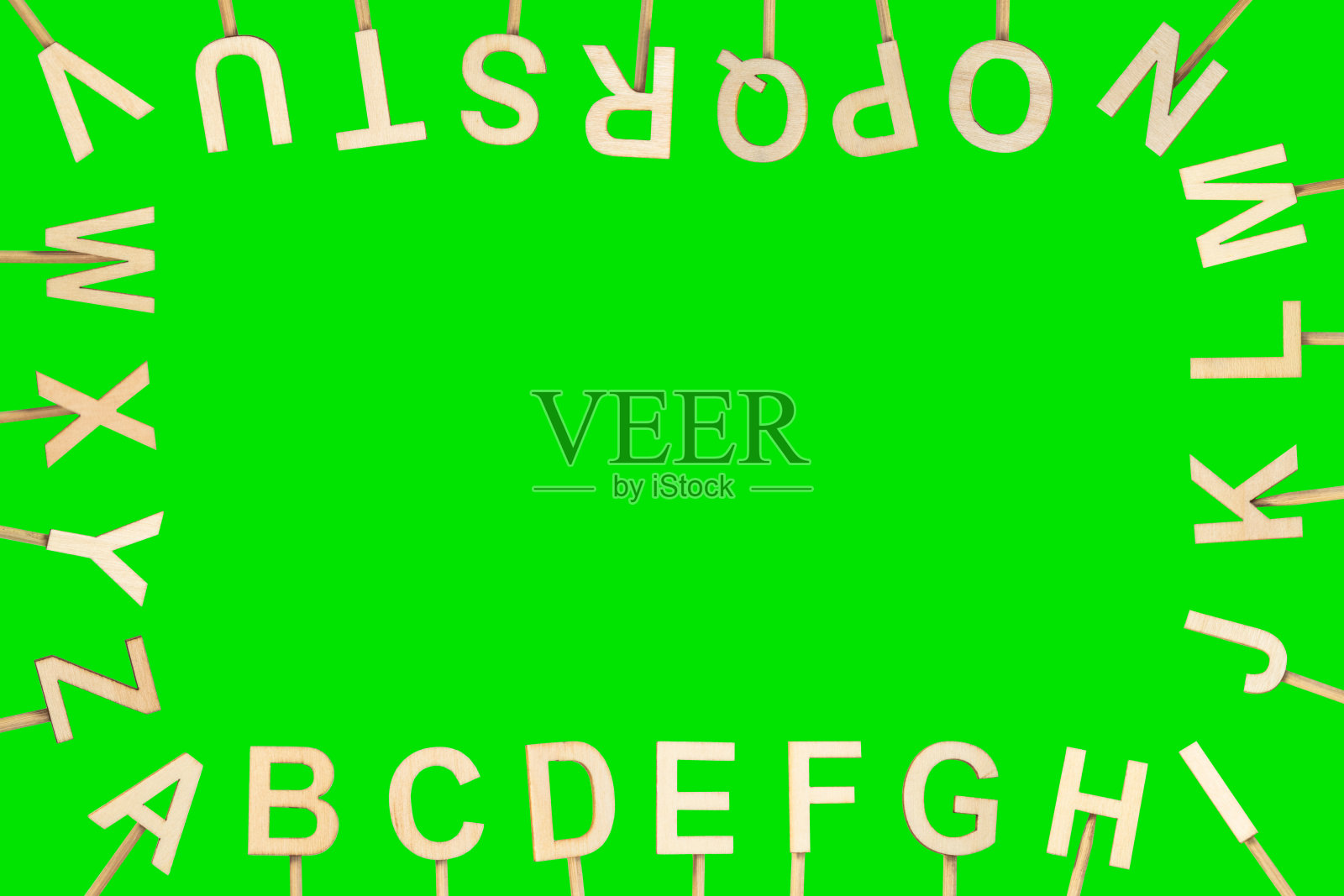 木制字母在屏幕周围形成字母表,中间有空余空间。绿色色度背景。照片摄影图片