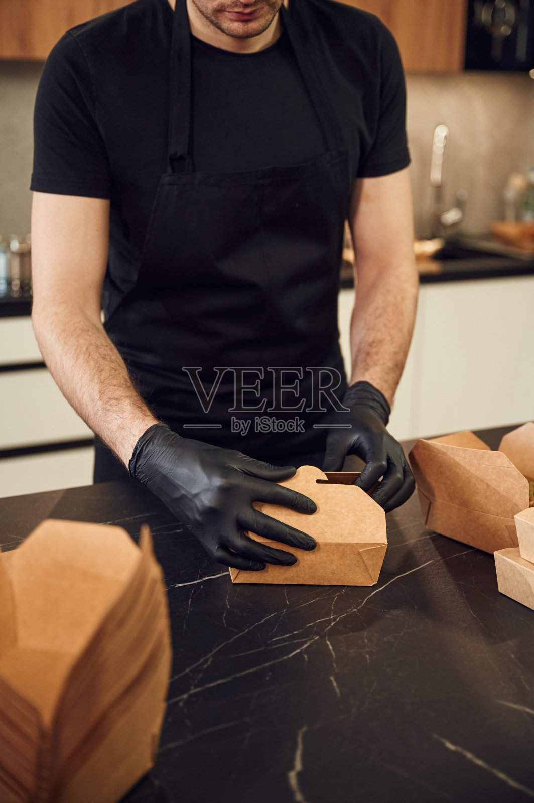 在桌子上。一个人正在把食物装进环保纸盒里。在室内,餐厅照片摄影图片