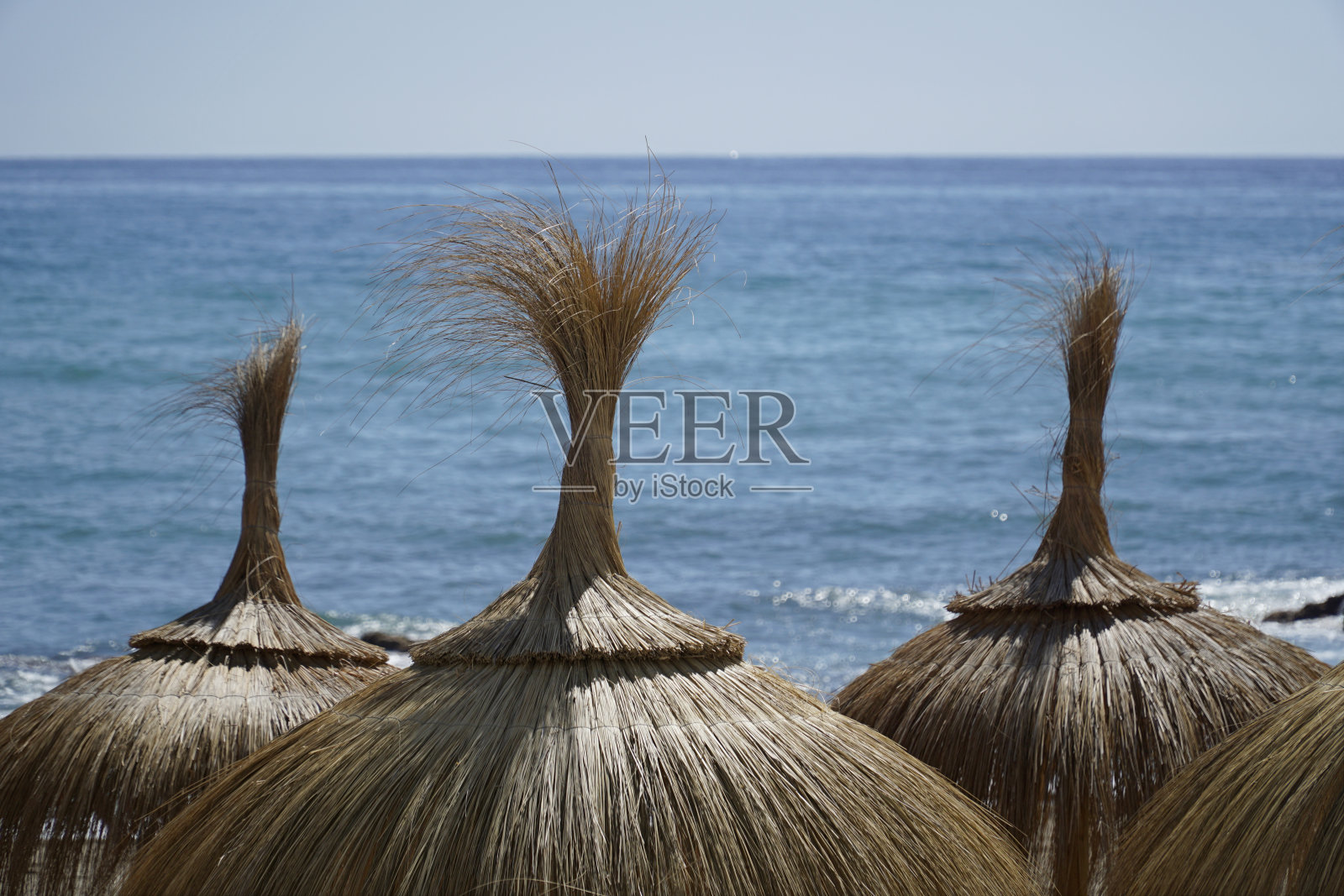 沙滩上的草伞照片摄影图片